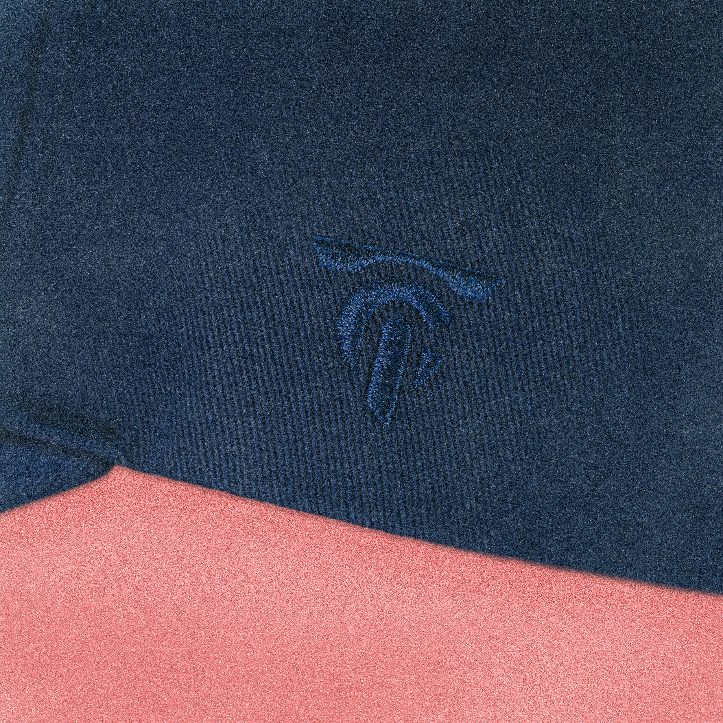 Close-up of a navy blue and pink fabric with an embroidered logo.