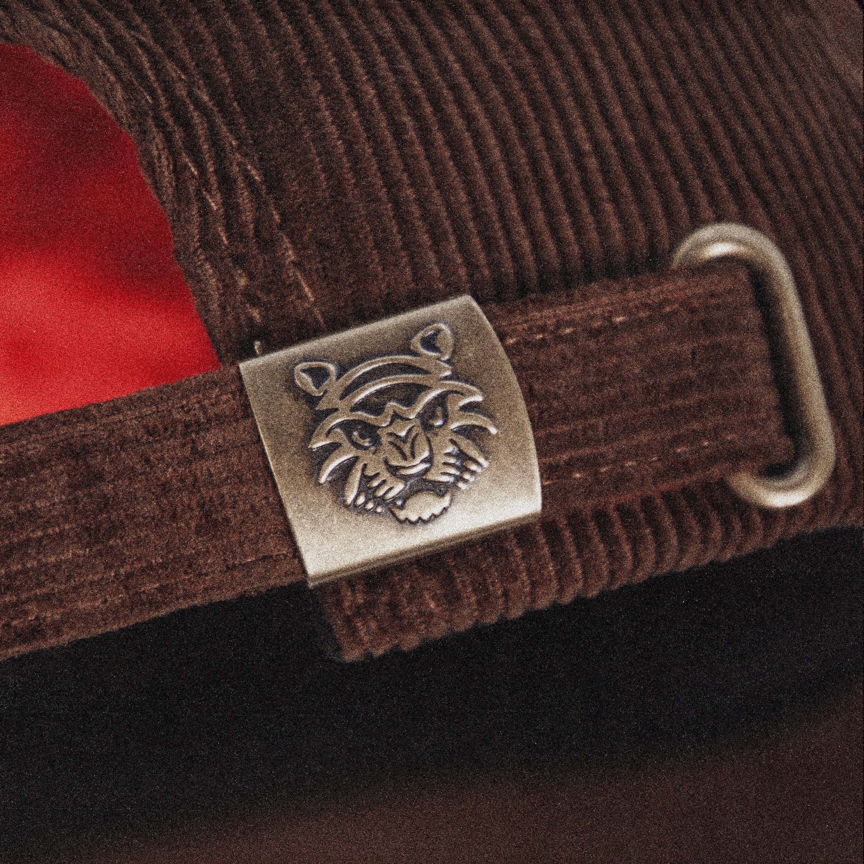 Close-up of the Tigerclaw Baskerville Canidrome corduroy cap featuring a custom engraved metal buckle, adjustable strap closure and premium headwear craftsmanship
