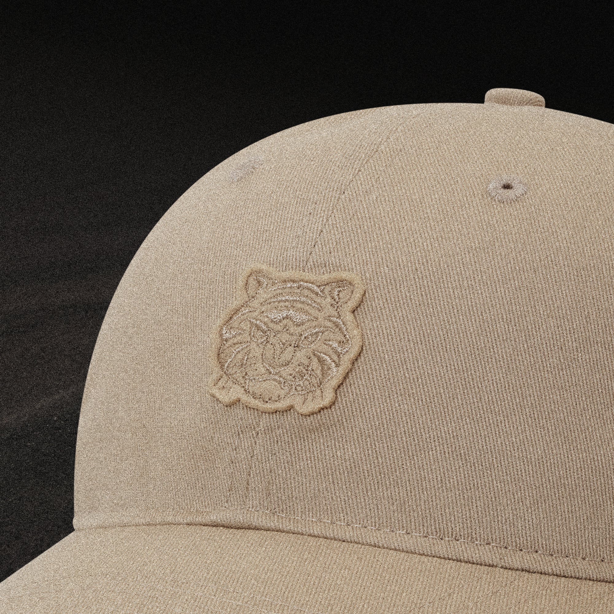 Beige cap with a tiger logo on a black background