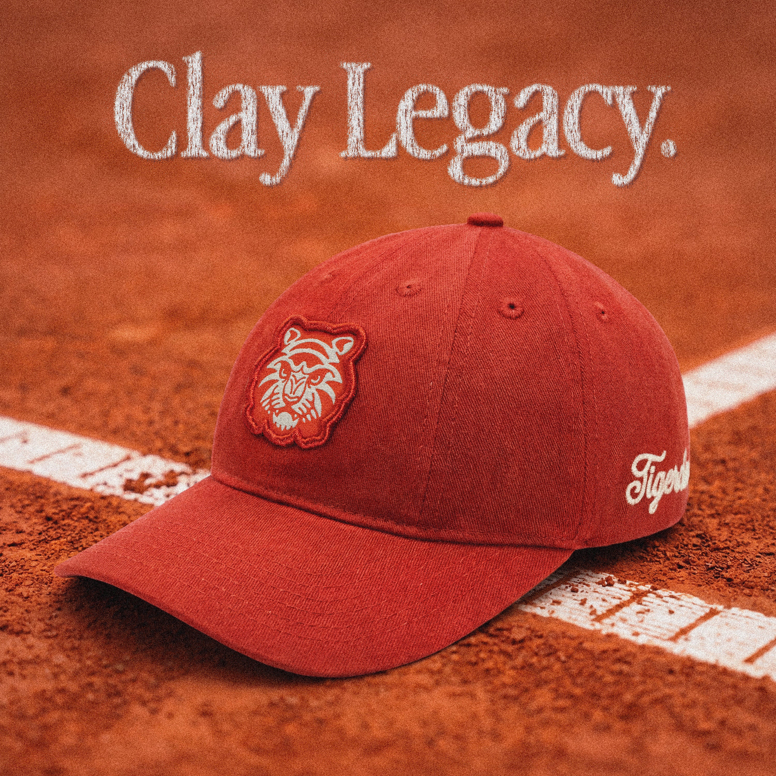 Clay Legacy 10-panel strapback cap by Tigerclaw Supplies in terracotta cotton twill, photographed on a clay tennis court with embroidered tiger patch and curved brim.
