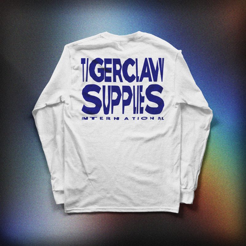 White long sleeve shirt with navy blue “TC” logo on the chest, displayed against a colorful gradient background.