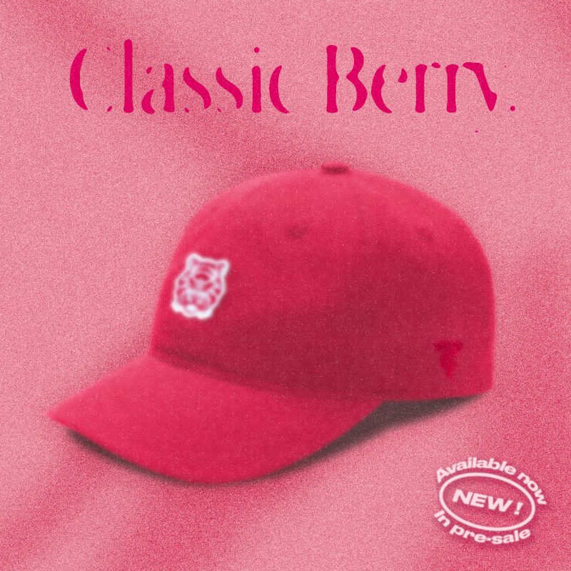 A red "Classic Berry" Tigerclaw strapback cap set against a matching pink-red background with bold serif text above and a circular "Available now" sticker in the corner.