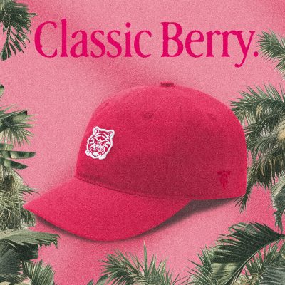A red "Classic Berry" Tigerclaw strapback cap set against a matching pink-red background with bold serif text above and a circular "Available now" sticker in the corner.