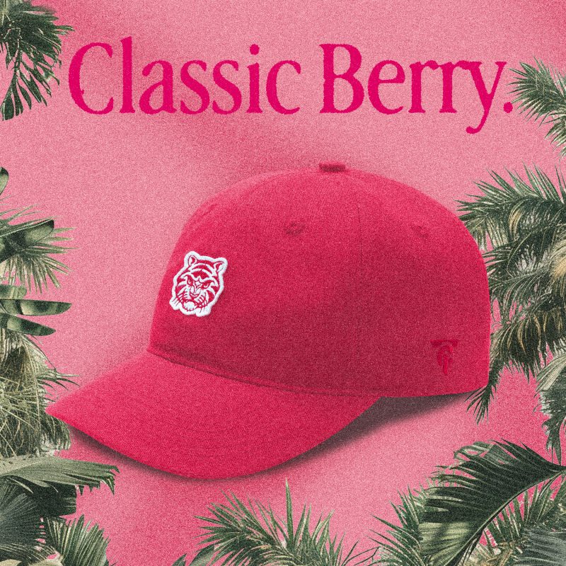 A red "Classic Berry" Tigerclaw strapback cap set against a matching pink-red background with bold serif text above and a circular "Available now" sticker in the corner.
