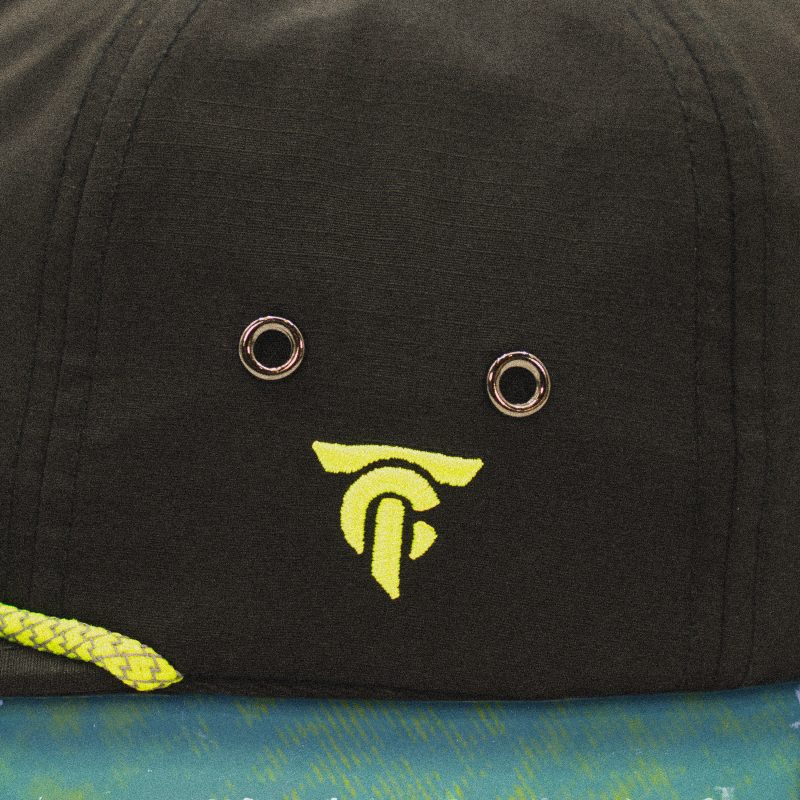 Close-up side view of black nylon cap showing two metal eyelets, neon green braided rope, and embroidered TC logo in high-vis yellow.
