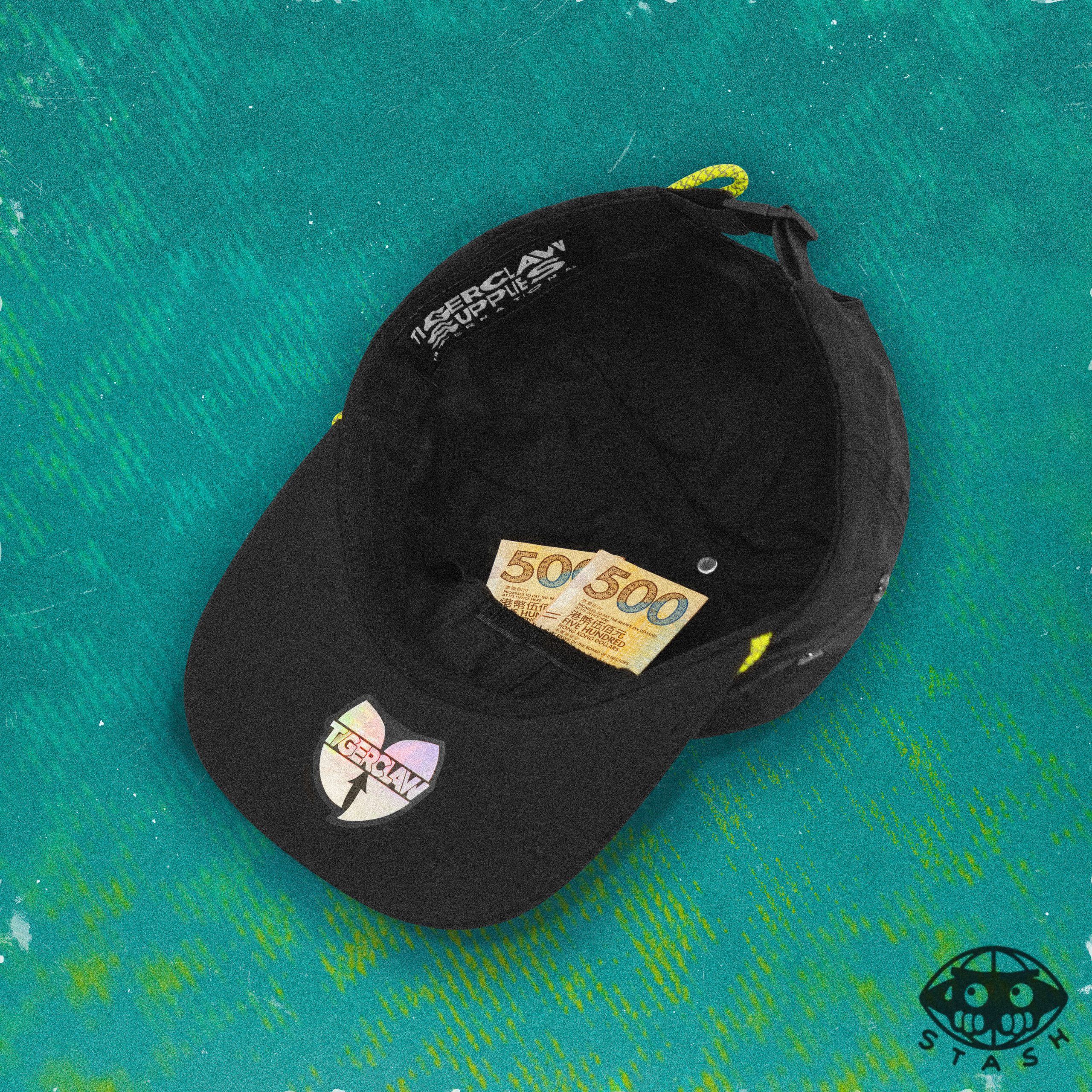 nside view of a black 6-panel cap showing hidden stash pocket with two 500 bills tucked in, set against a textured teal background. Features a Tigerclaw holographic sticker and “STASH” icon.