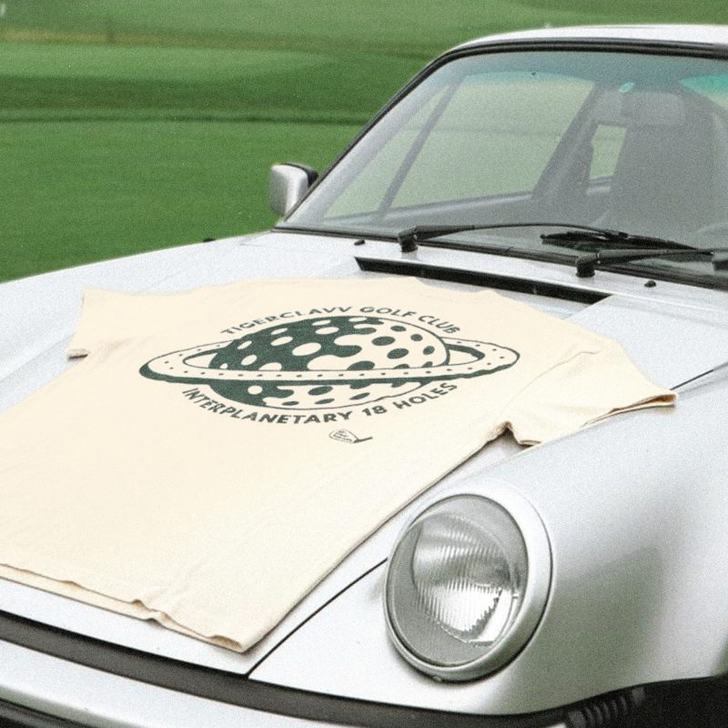 Tigerclaw Golf Club Tee laid flat on vintage car hood at the golf course